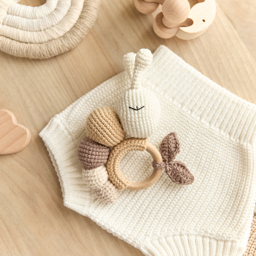 Handmade crochet caterpillar baby rattle with wooden teething ring — flat lay