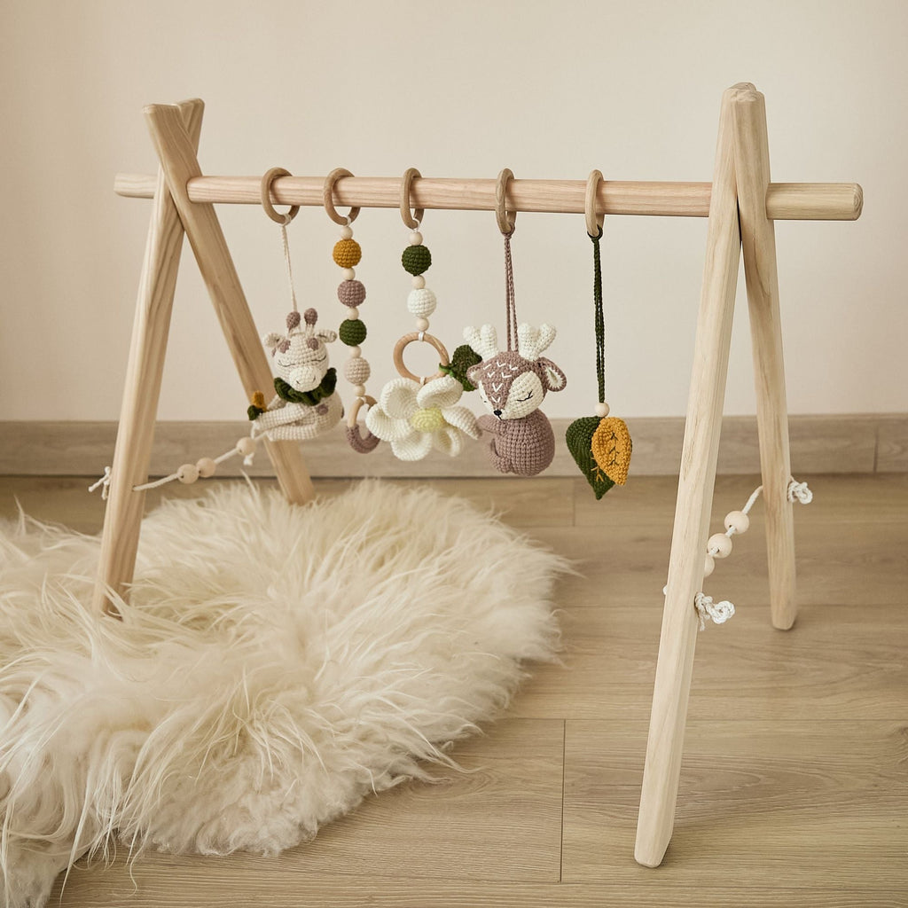 Baby playing under wooden play gym — close-up of hanging crochet toy reach