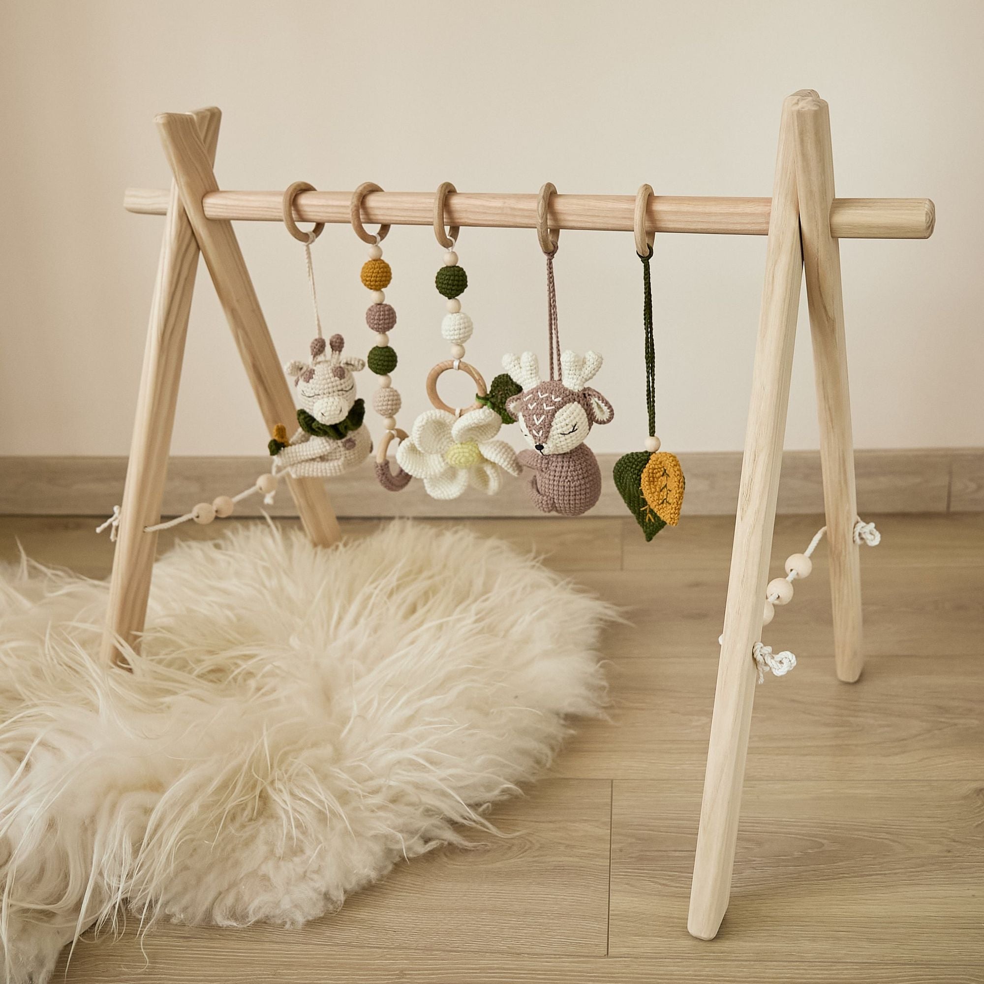Baby playing under wooden play gym — close-up of hanging crochet toy reach