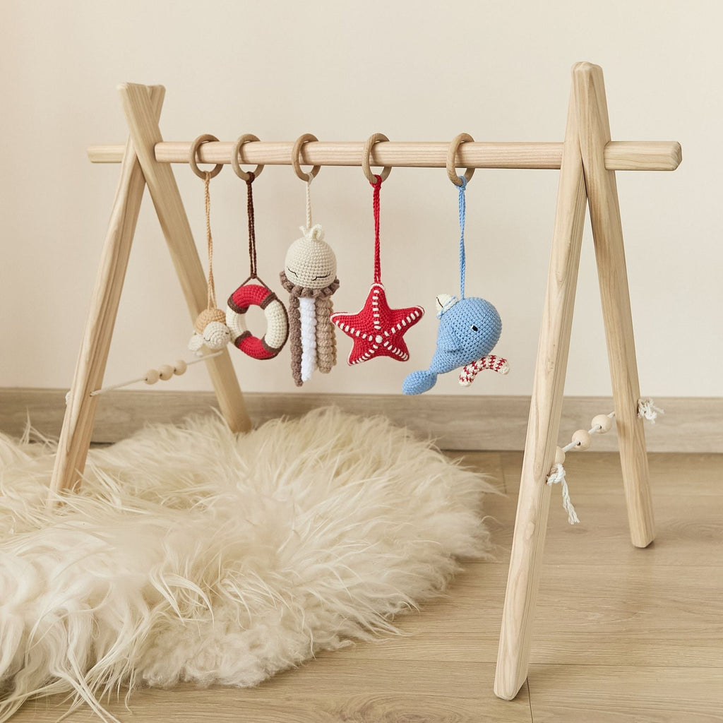 Wooden baby gym with baby reaching for hanging crochet elephant toy